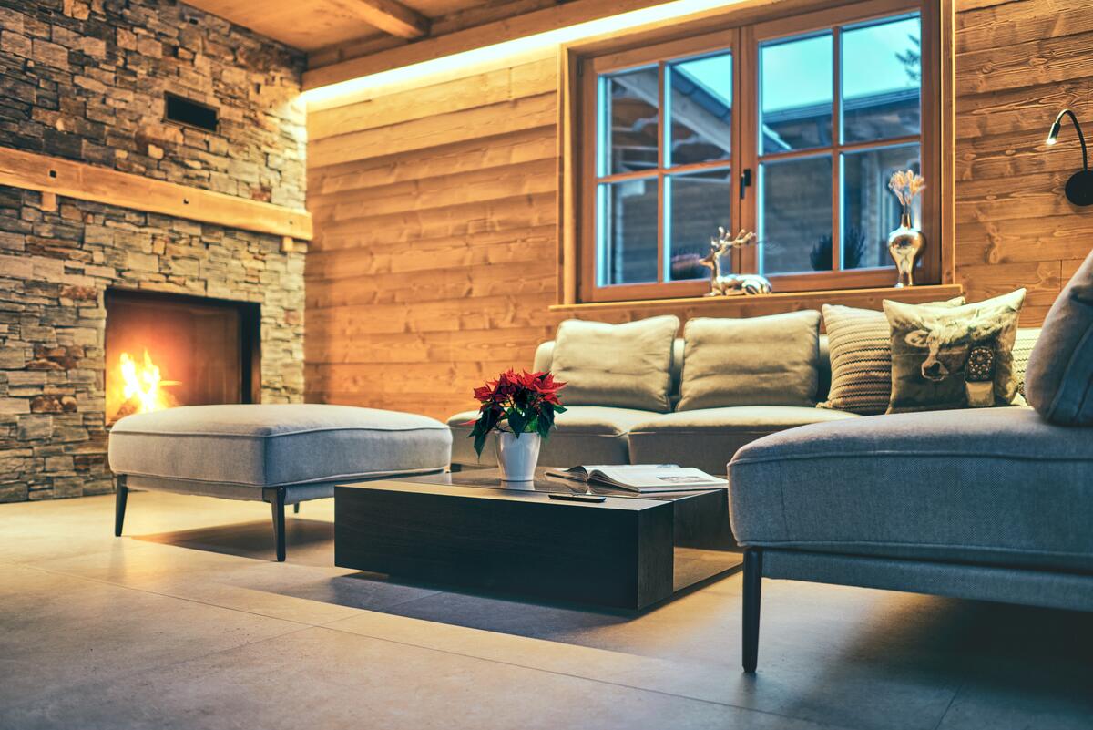 Wohnbereich mit Kamin, Naturstein und warmem Licht im Chalet